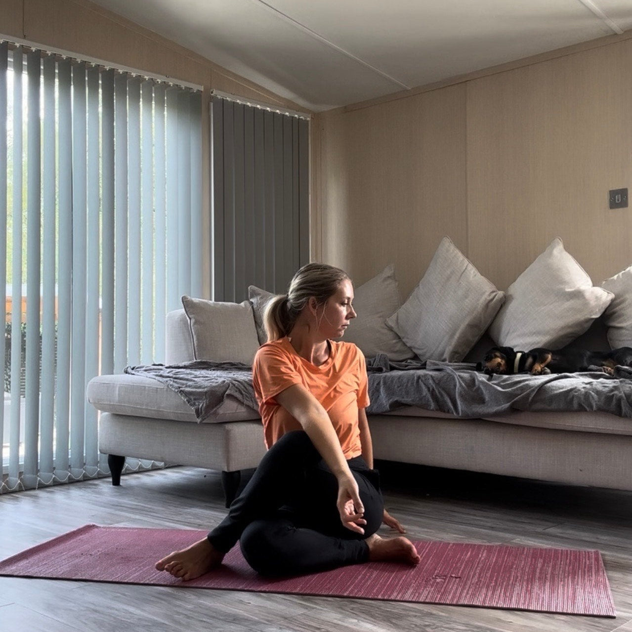 Woman practicing yoga on a mat in a living room.