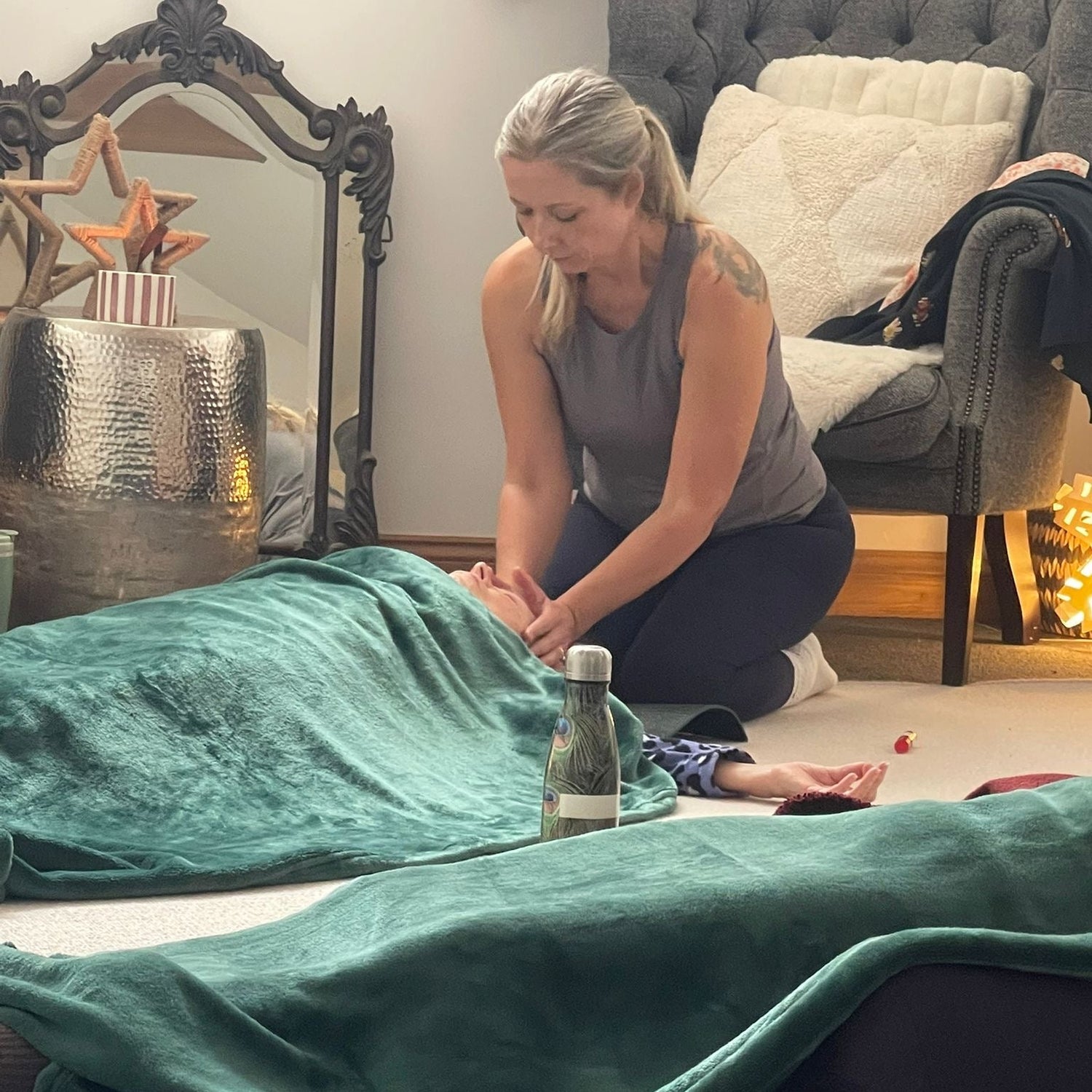 Person receiving a reiki energy heaaling sessionon a green blanket in a home setting.